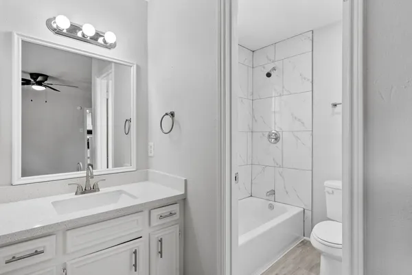 a bathroom with a tub a sink shower mirror and a toilet