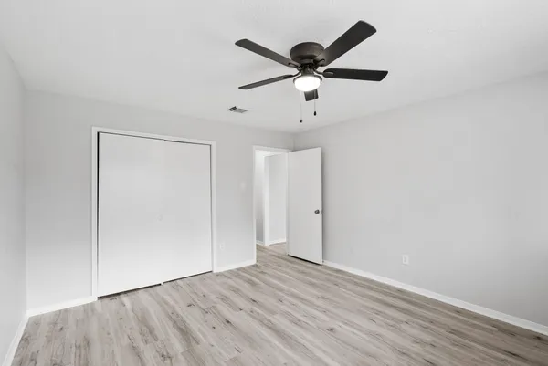 an empty room with wooden floor and a ceiling fan