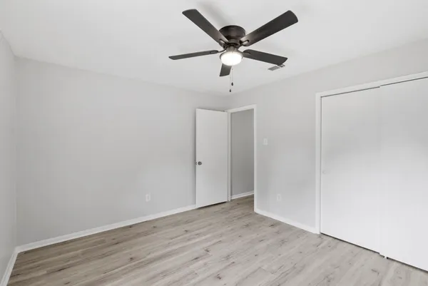 an empty room with wooden floor and ceiling fan