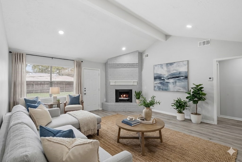 23111 Canyon Lake Drive Spring, TX 77373 - Photo 2 of 24 Living room with vaulted ceiling, recessed lighting, and brick fireplace with painted surround as the focal point. Large rear window overlooks the backyard, and the space is shown virtually staged to illustrate seating arrangements.