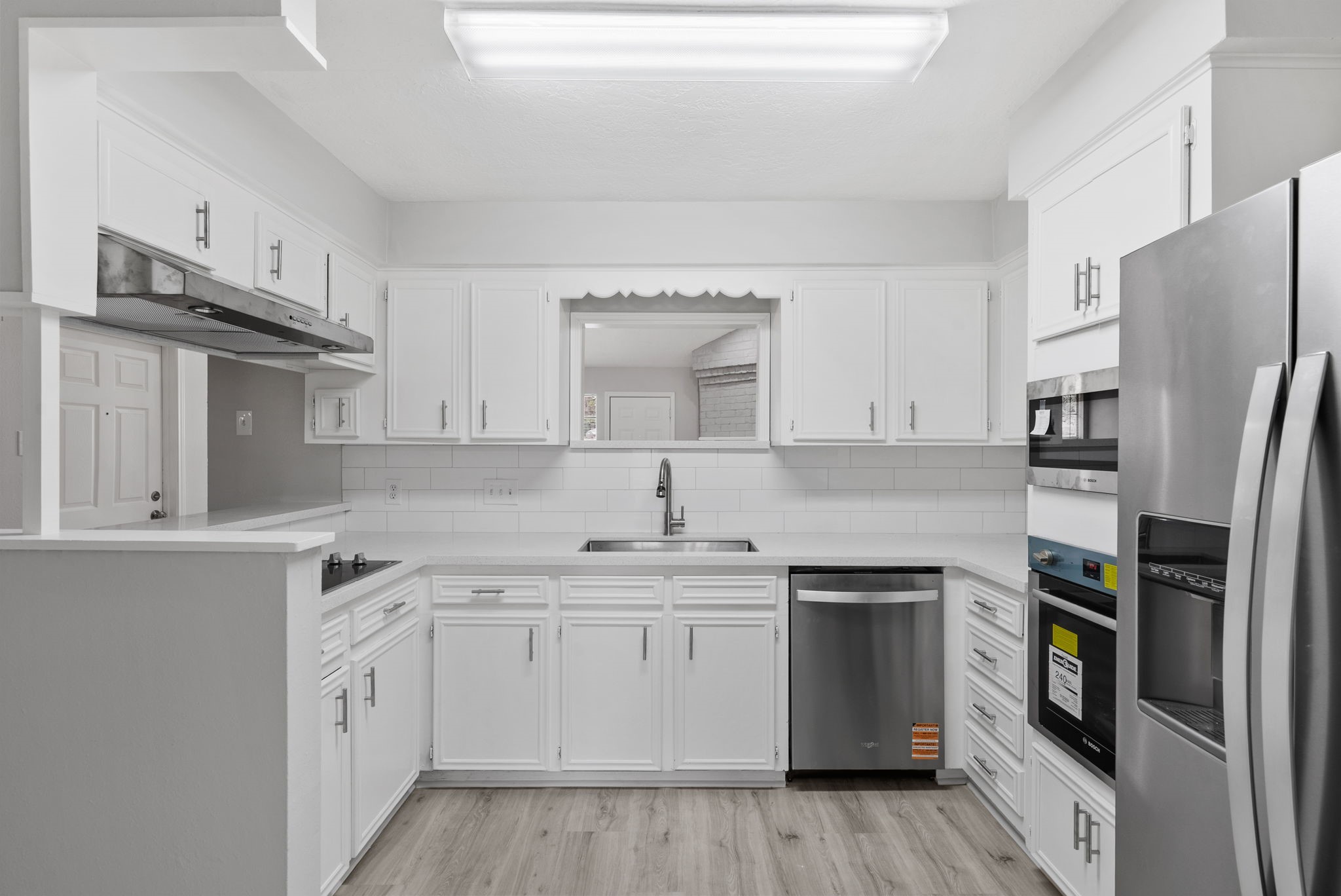 23111 Canyon Lake Drive Spring, TX 77373 - Photo 8 of 24 Kitchen combines classic white cabinetry with sleek solid-surface counters, subway tile backsplash, and stainless appliances, giving the cook a bright, functional workspace that stays visually connected to the living area through the pass-through opening.