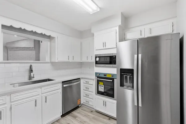 a kitchen with white cabinets and stainless steel appliances