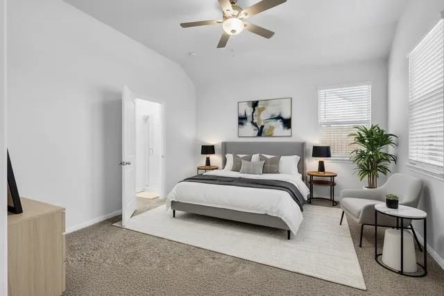 a spacious bedroom with a bed a couch and potted plant on the dresser