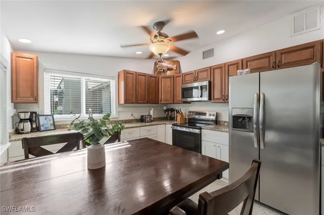 a kitchen with granite countertop stainless steel appliances cabinets a dining table and a chandelier