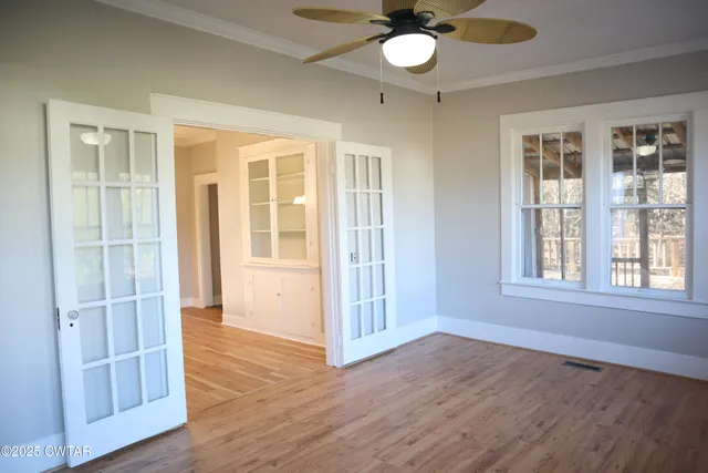 an empty room with wooden floor fan and windows