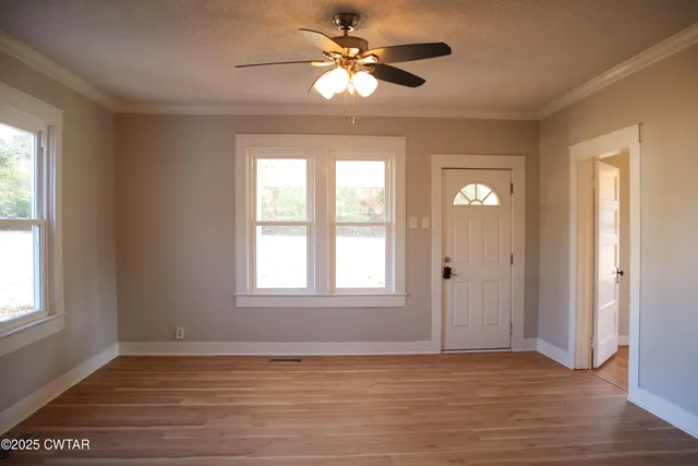 a view of an empty room with a window and wooden floor