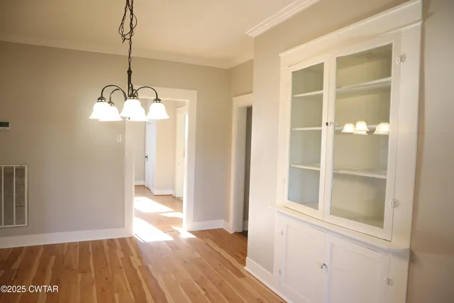 a view of a room with wooden floor chandeliers and kitchen