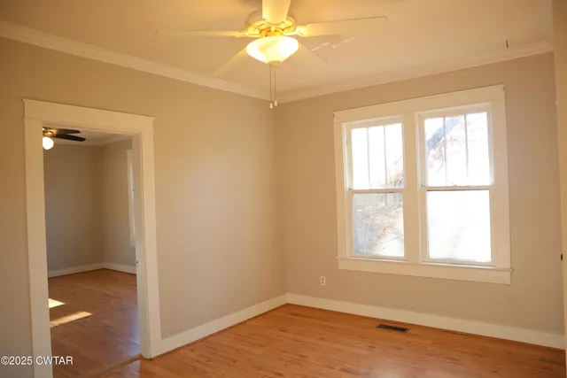 a view of an empty room with wooden floor and a window