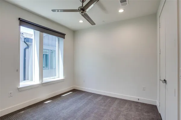 an empty room with a window and ceiling fan