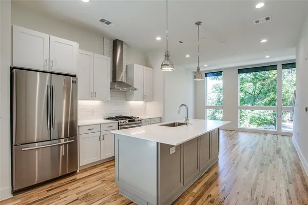 a kitchen a sink a refrigerator a stove and cabinets with wooden floor