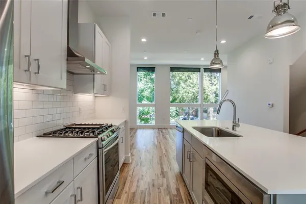 a kitchen with granite countertop a stove a sink dishwasher and a microwave oven with white cabinets