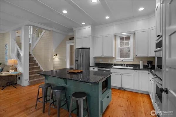 a kitchen with stainless steel appliances granite countertop sink stove top oven and cabinets