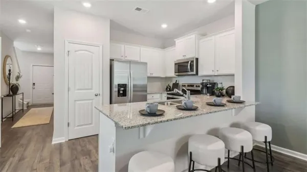 a kitchen with stainless steel appliances granite countertop a sink a stove a refrigerator and a refrigerator