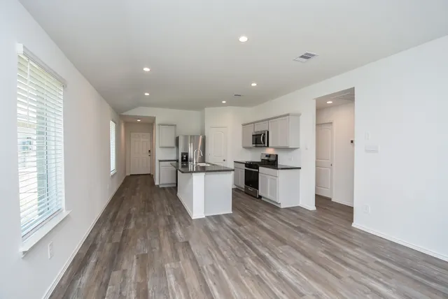 an empty room with wooden floor and windows