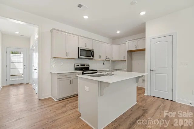a kitchen with a refrigerator a stove top oven a sink and cabinets