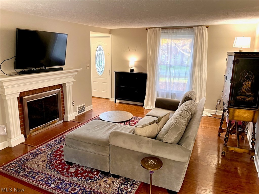 38095 Aurora Road Solon, OH 44139 - Photo 2 of 17 Living room with hardwood / wood-style floors, a brick fireplace, and a textured ceiling