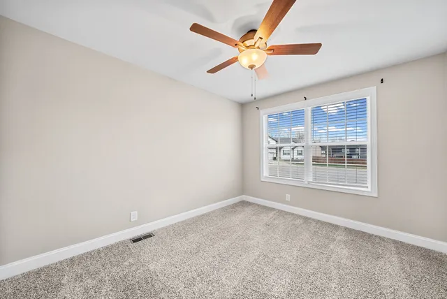an empty room with a ceiling fan and window