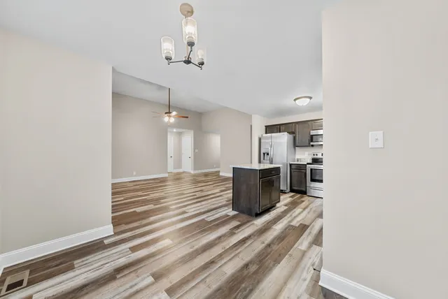 a view of a room with wooden floor white walls and chandelier