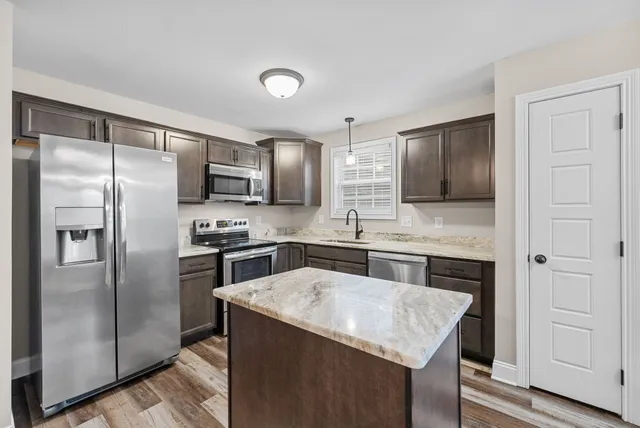 a kitchen with stainless steel appliances granite countertop a refrigerator a stove a sink and a microwave