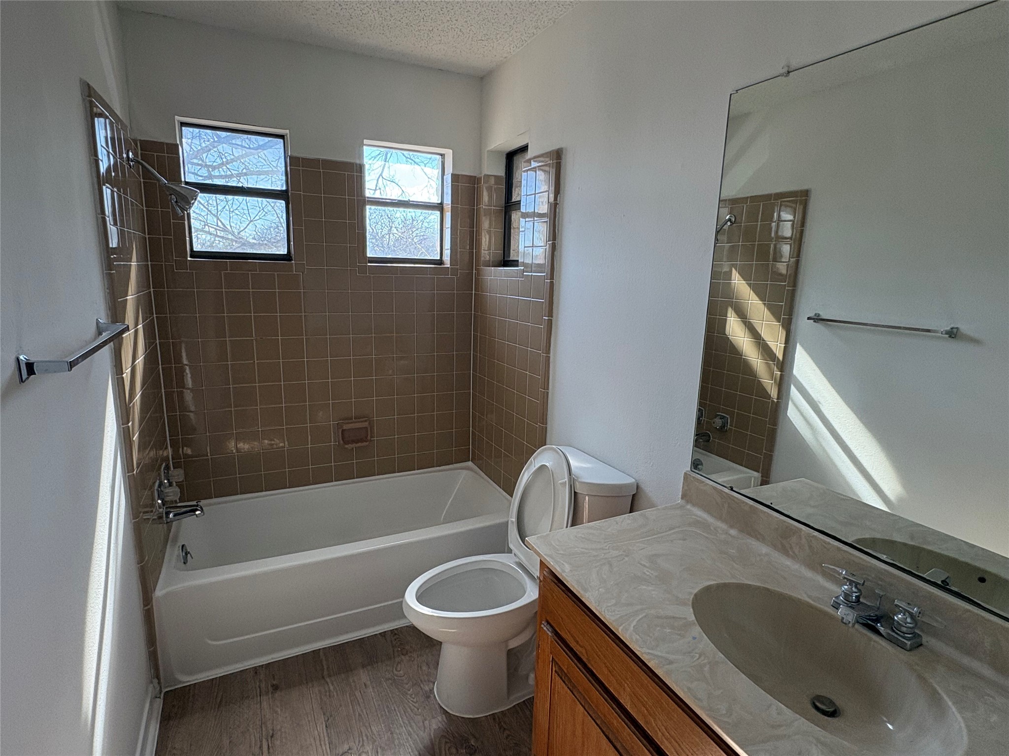 9201 Simmons Road, Unit 119 Austin, TX 78759 - Photo 11 of 22 Bathroom with shower / bathtub combination, vanity, dark wood-style floors, and a textured ceiling
