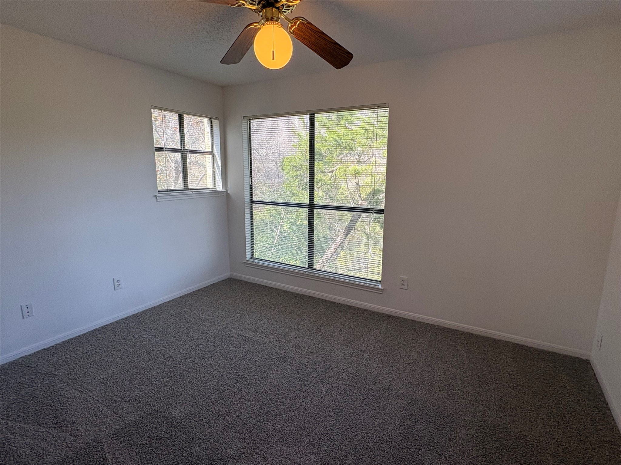 9201 Simmons Road, Unit 119 Austin, TX 78759 - Photo 12 of 22 Unfurnished room with dark colored carpet, a ceiling fan, healthy amount of natural light, and a textured ceiling
