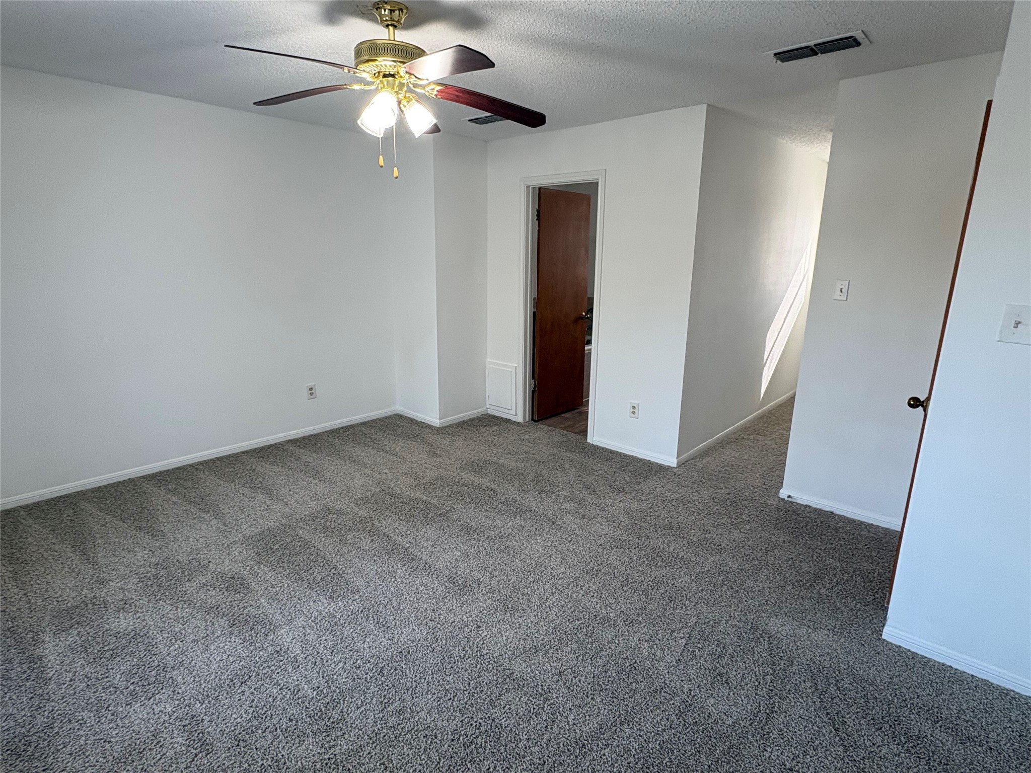 9201 Simmons Road, Unit 119 Austin, TX 78759 - Photo 16 of 22 Unfurnished bedroom featuring dark carpet, a ceiling fan, and a textured ceiling