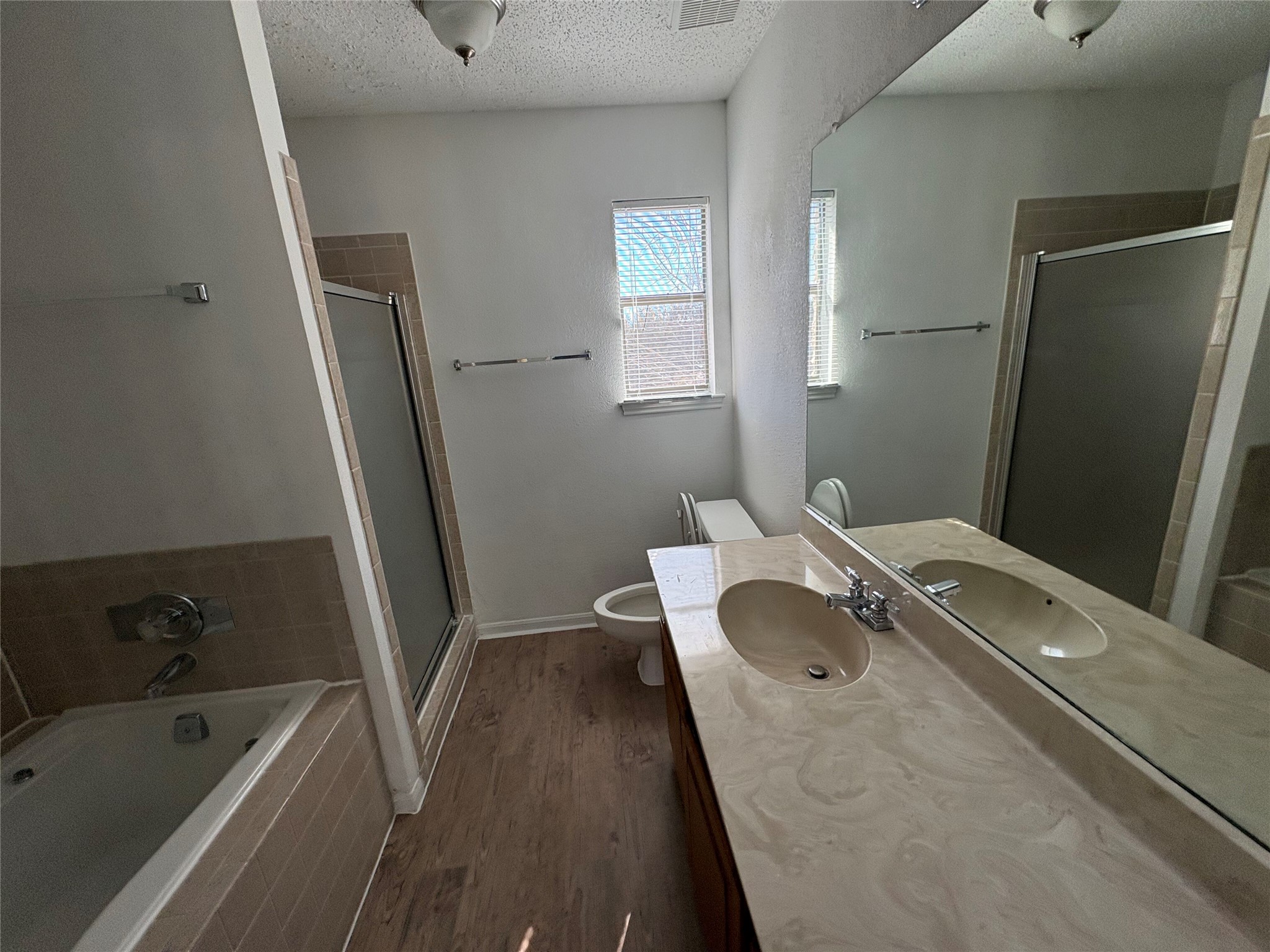 9201 Simmons Road, Unit 119 Austin, TX 78759 - Photo 18 of 22 Full bath featuring vanity, a bath, dark wood finished floors, a shower stall, and a textured ceiling