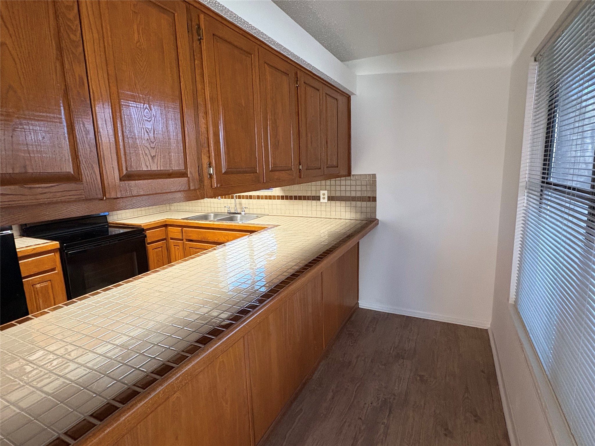 9201 Simmons Road, Unit 119 Austin, TX 78759 - Photo 8 of 22 Kitchen with tile counters, electric range, dark wood-style floors, and tasteful backsplash
