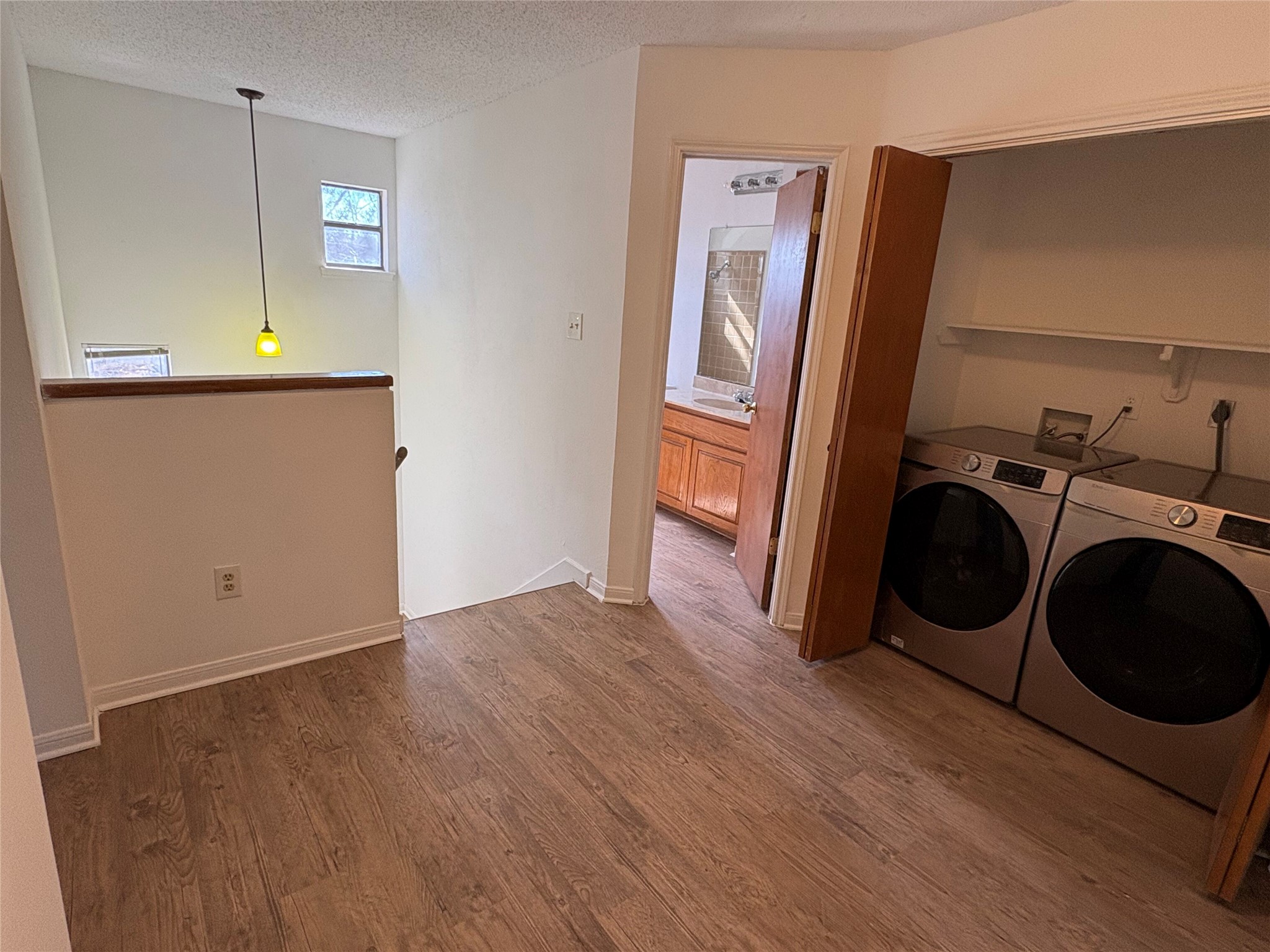 9201 Simmons Road, Unit 119 Austin, TX 78759 - Photo 9 of 22 Laundry room with wood finished floors, a textured ceiling, and washing machine and clothes dryer