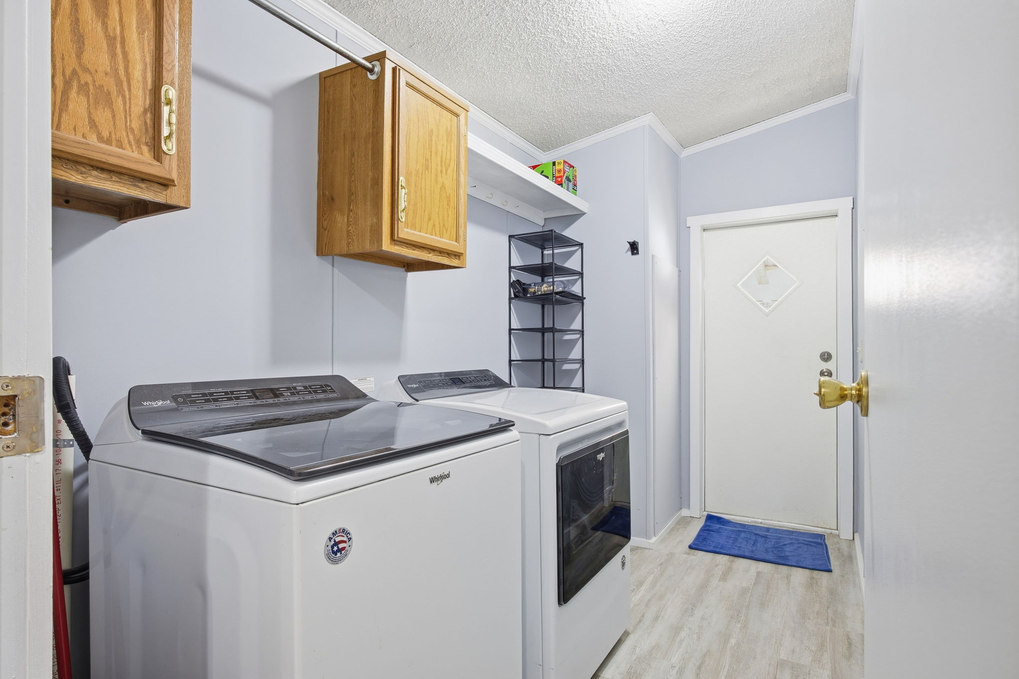 182 Wayside Court Elgin, TX 78621 - Photo 11 of 40 Laundry room with a textured ceiling, light wood-style floors, cabinet space, ornamental molding, and washing machine and dryer