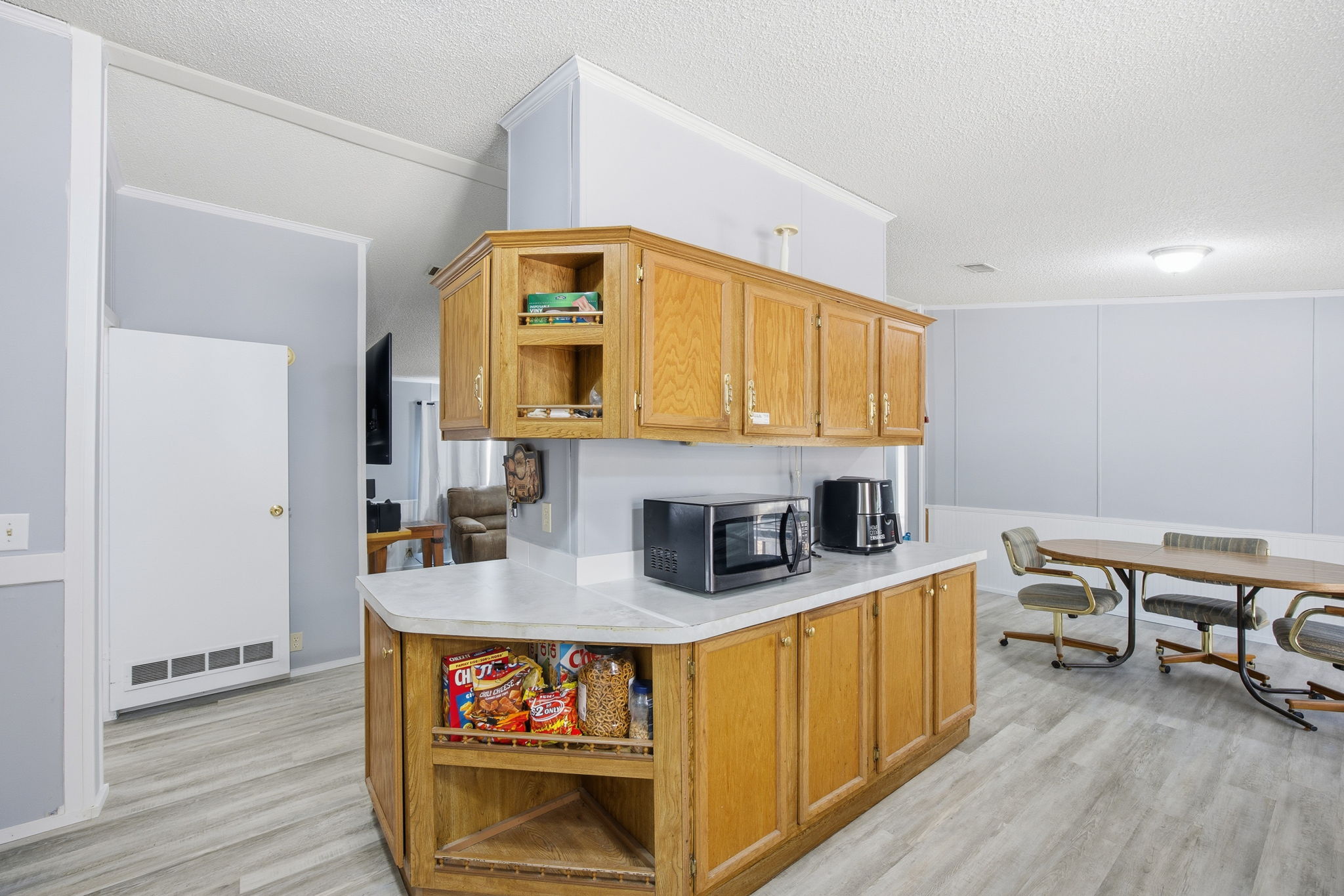 182 Wayside Court Elgin, TX 78621 - Photo 9 of 40 Kitchen featuring open shelves, light countertops, a textured ceiling, light wood-type flooring, and stainless steel microwave