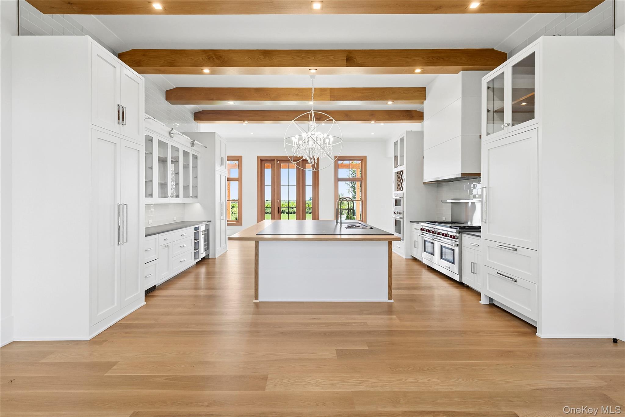 522 Wickapogue Road Southampton, NY 11968 - Photo 14 of 49 a large white kitchen with kitchen island a large window a sink and stainless steel appliances
