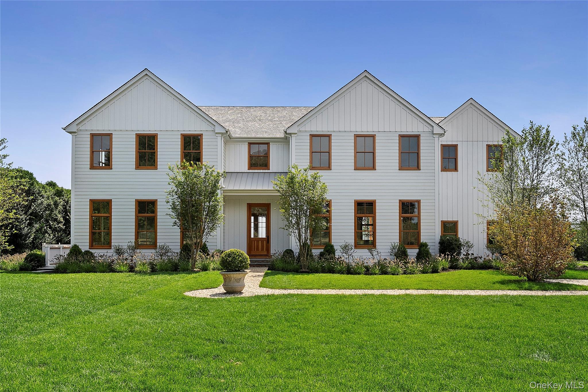 522 Wickapogue Road Southampton, NY 11968 - Photo 43 of 49 a front view of a white house with a yard and large trees