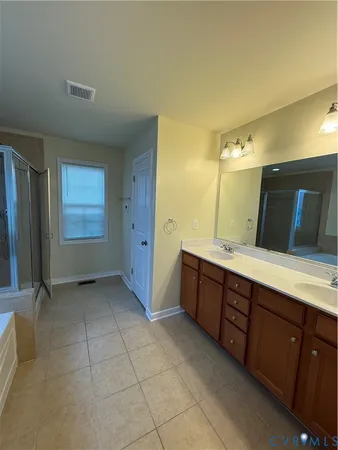 a bathroom with a double vanity sink a large mirror and a bathtub