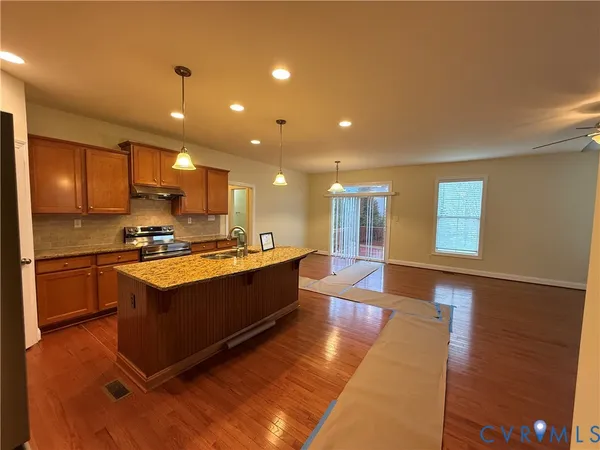 a large kitchen with stainless steel appliances granite countertop a stove a sink and a refrigerator