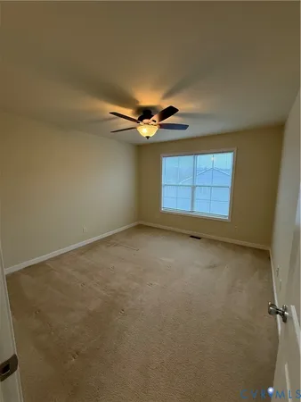 an empty room with a ceiling fan and window