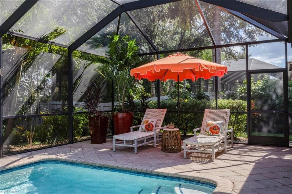 7263 Acorn Way Naples, FL 34119 - Photo 23 of 34 a view of backyard with swimming pool table and chairs under an umbrella