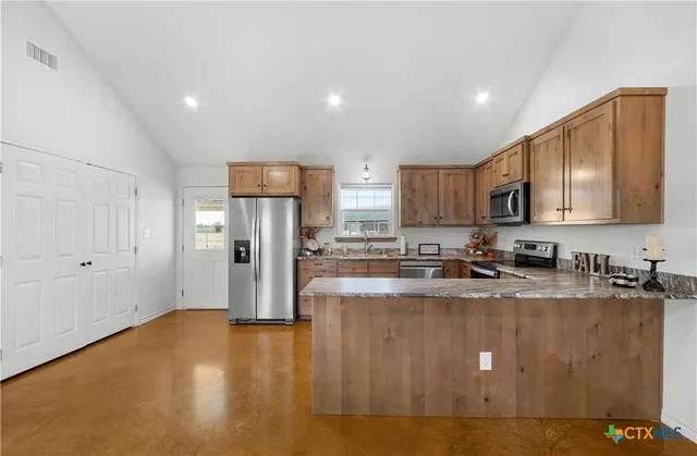 a kitchen with stainless steel appliances granite countertop a refrigerator a stove a sink a refrigerator and white cabinets with wooden floor