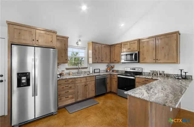 a kitchen with granite countertop a refrigerator stove top oven and sink