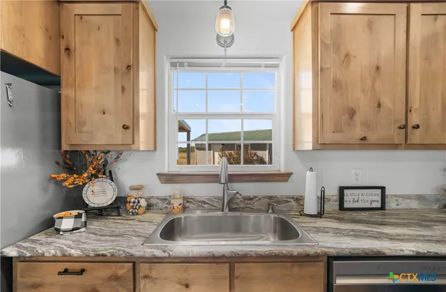 a kitchen with granite countertop a sink a stove and cabinets