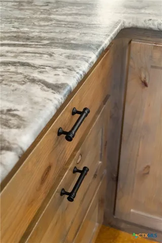 a kitchen with granite countertop a stove a sink and a white wooden cabinets