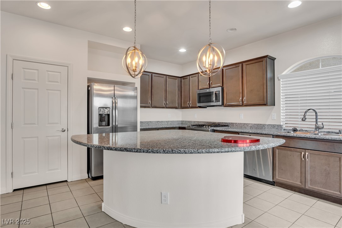 10073 Icicle Ridge Las Vegas, NV 89141 - Photo 7 of 23 Kitchen featuring stainless steel appliances, a chandelier, light tile patterned floors, dark stone counters, and recessed lighting