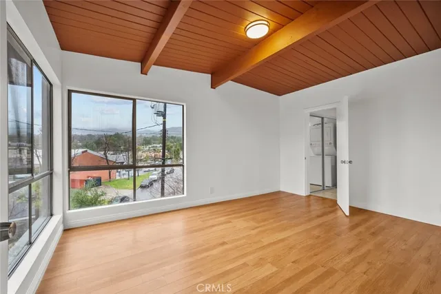an empty room with wooden floor and windows