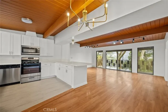 a view of a kitchen with wooden floor and electronic appliances