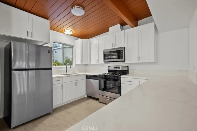 a kitchen with stainless steel appliances granite countertop a refrigerator a stove top oven a sink and dishwasher