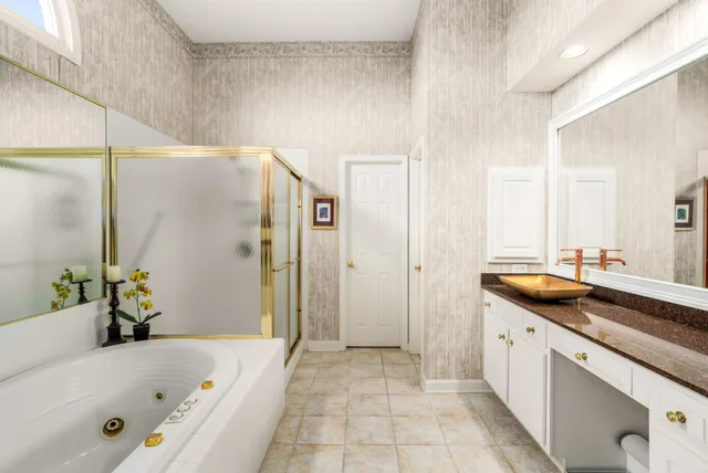a bathroom with a granite countertop tub sink and mirror