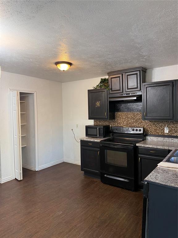 3801 Guthrie Road Garland, TX 75043 - Photo 4 of 24 Kitchen featuring wood-finish flooring, dark cabinetry, mosaic tile backsplash, and built-in pantry shelving