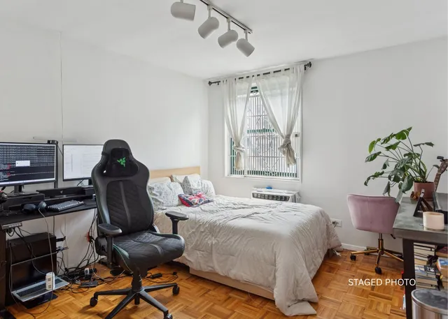 a bedroom with a bed and a computer on a desk next to a window