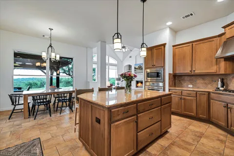 a kitchen with kitchen island granite countertop a stove a sink a oven a dining table and chairs