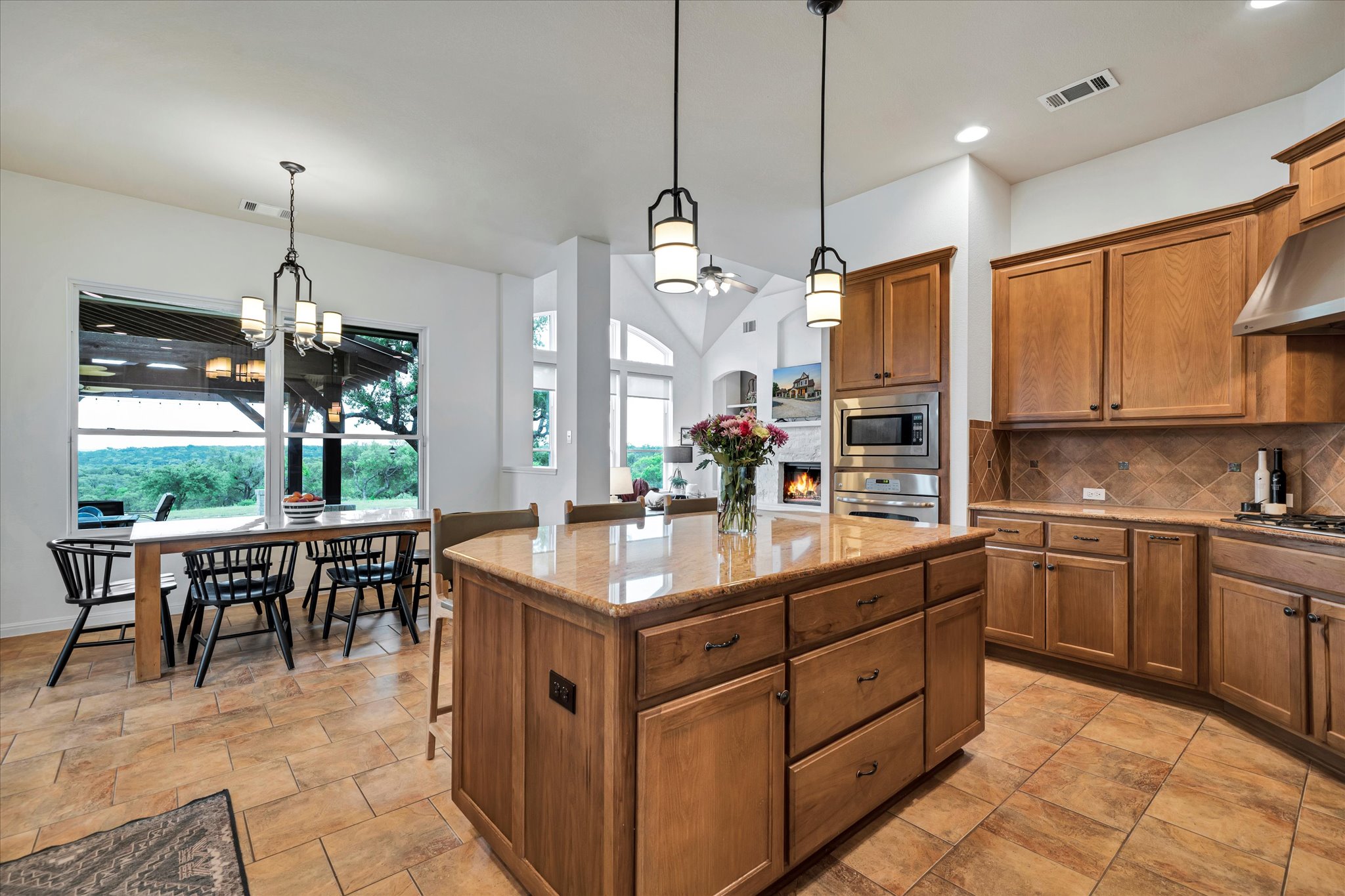 440 Currie Ranch Road Wimberley, TX 78676 - Photo 10 of 40 a kitchen with kitchen island granite countertop a stove a sink a oven a dining table and chairs